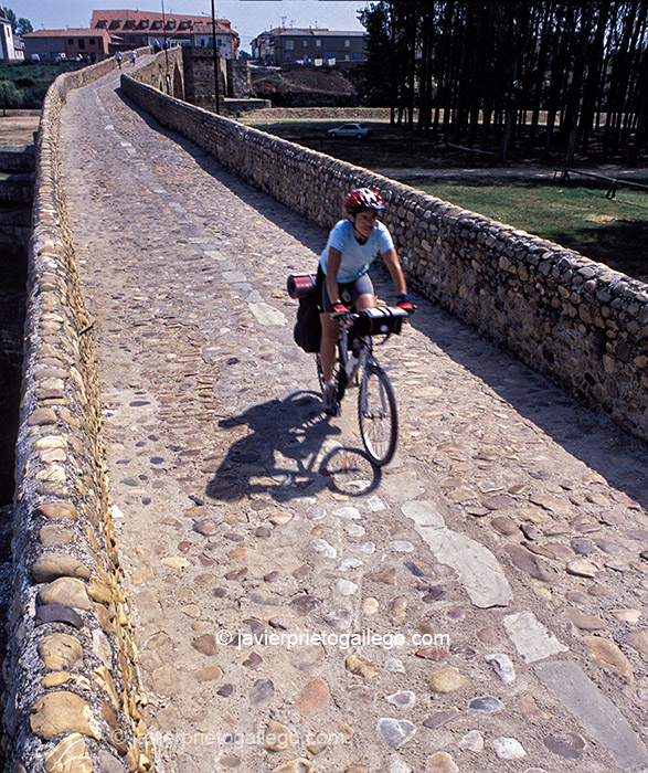 Una peregrina pasa en bicicleta sobre el puente medieval de Hospital de Órbigo. Camino de Santiago Francés. León. Castilla y León. España. © Javier Prieto Gallego